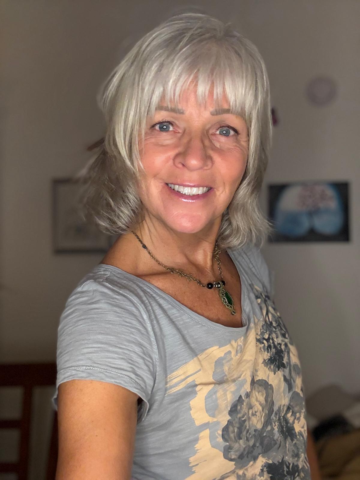 Sharon-Cusack-Wellness Sharon Cusack, Integrative Health Coach and Energy Medicine Specialist, smiling in a beachside setting, embodying holistic wellness.